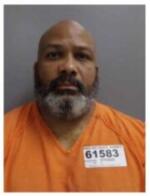 Front-facing mugshot of a man with a gray beard wearing an orange inmate jumpsuit; inmate ID 61583 visible on the chest badge.