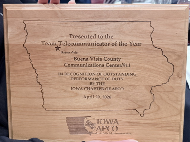 Wooden plaque engraved with Iowa outline, awarded to Buena Vista County Communications Center/911 as Team Telecommunicator of the Year, dated April 20, 2026, with Iowa APCO seal and slogan.