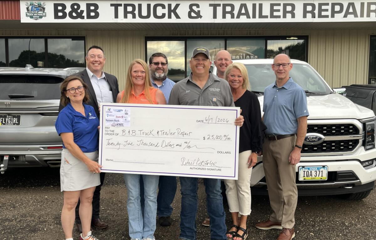 Eight people stand in front of a B&B Truck & Trailer Repair storefront, holding a large ceremonial check for $25,000 dated June 17, 2026.