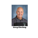 Portrait of Greg Ebeling, smiling, wearing a gray polo with a Pella logo against a blue background.