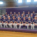 Group photo of a high school baseball team in purple uniforms labeled 'TIGERS' on gym bleachers, with coaches in back row.