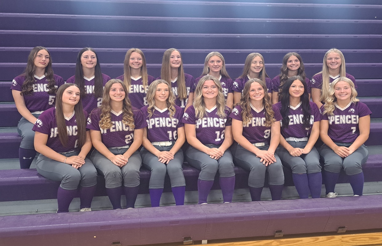 Group of girls in purple Spencer softball jerseys posing on gym bleachers.